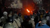 Police stand ready as vehicles burn after clashes. Pic: Reuters