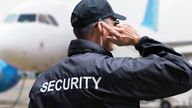 Rear view of mature security guard listening to earpiece against building