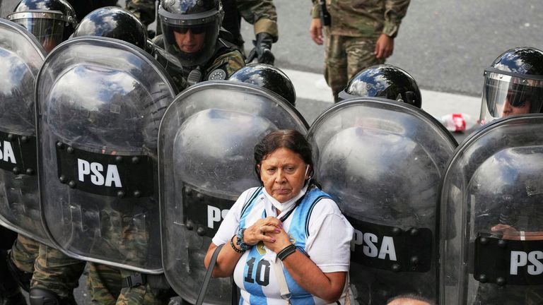 A woman stands in front of riot police during the protest. Pic: AP