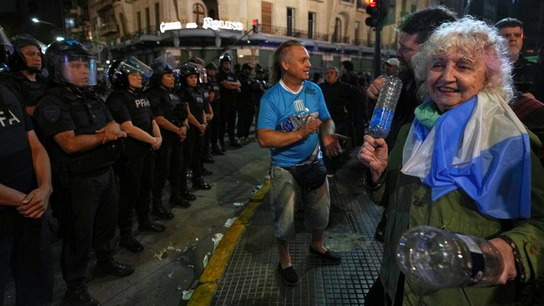 A woman bangs plastic bottles together during a protest for higher pensions. Pic: AP