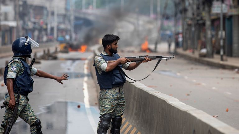 A policeman aims his weapon at protesters during an imposed curfew on 5 August.
Pic: Reuters/Rajib Dhar