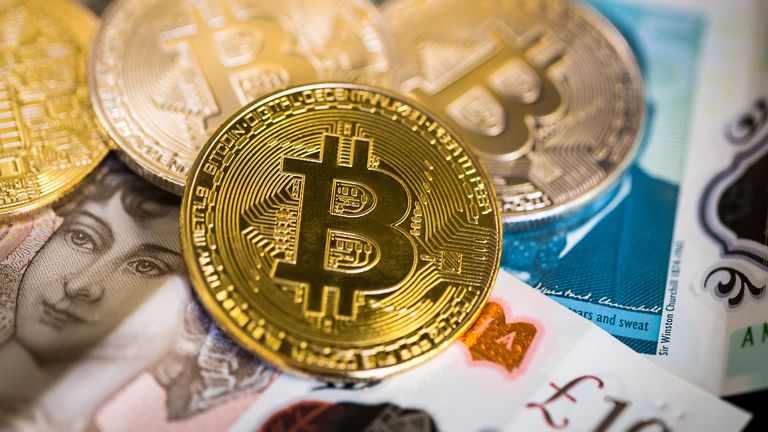 London, UK - January 23, 2018: close up color image depicting a collection of shiny gold and silver colored Bitcoins, the physical manifestation of the digital virtual cryptocurrency. The Bitcoins are resting on top of a pile of British pound bank notes, including the £5, £10 and £20 note. Plenty of room for copy space.

