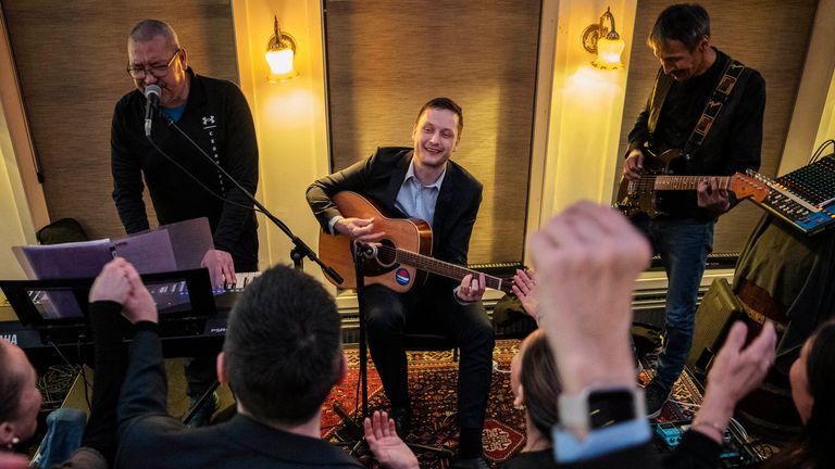 Chairman of Demokraatit, Jens-Frederik Nielsen, center, plays guitar as he reacts during the election party at Demokraatit by cafe Killut in Nuuk, early Wednesday, March 12, 2025. (Mads Claus Rasmussen/Ritzau Scanpix via AP)