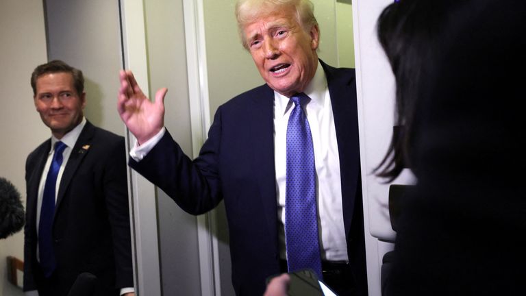 Donald Trump speaks to reporters, watched by National Security Advisor Mike Waltz, aboard Air Force One.
Pic: Reuters