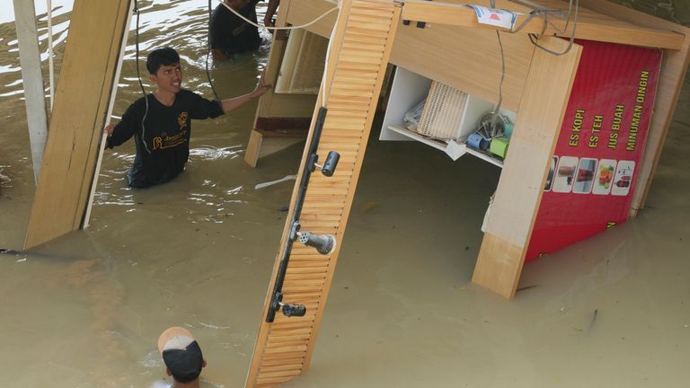 Workers try to clean up the parking area of a shopping mall after flooding from heavy downpours in Bekasi on the outskirts of Jakarta, Indonesia, Wednesday, March 5, 2025. Pic: AP