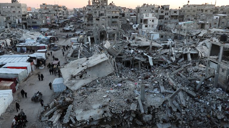 Palestinians walk among the rubble of buildings, amid a ceasefire between Israel and Hamas, in Khan Younis, in the southern Gaza Strip, February 27, 2025. REUTERS/Ramadan Abed