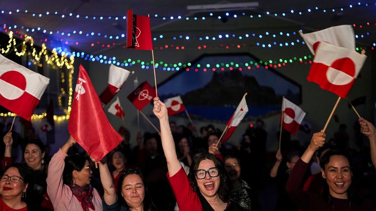 Members of Inuit Ataqatigiit political party dance with national flags at a party after parliamentary elections in Nuuk, Greenland, Tuesday, March 11, 2025. (AP Photo/Evgeniy Maloletka)