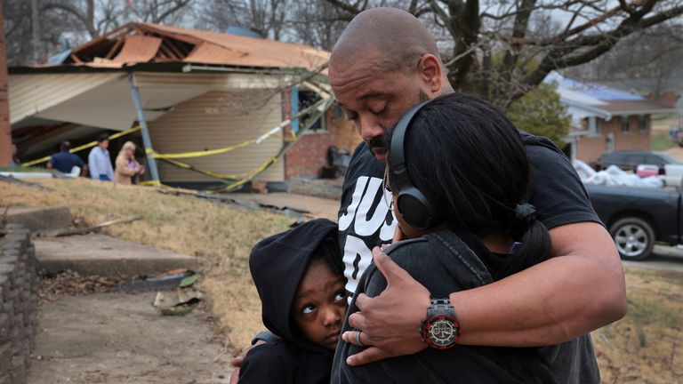 Marcus Cole embraces his daughters while standing in front of his destroyed home after a severe storm in Bridgeton, Mo., Saturday, March 15, 2025.  (Robert Cohen/St. Louis Post-Dispatch via AP)