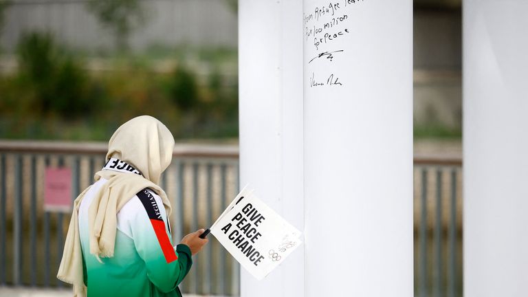 An athlete holding a flag stands next to a pillar with writing on it during the Olympic Truce event.
Pic: Reutrers