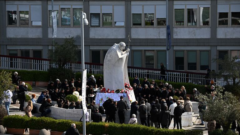 People pray for Pope Francis at the statue of the late pope John Paul II. Pic: Reuters