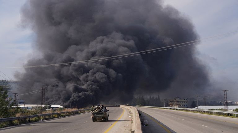 FILE PHOTO: Smoke rises while members of the Syrian forces ride on a vehicle as they battle against a nascent insurgency by fighters from ousted leader Bashar al-Assad's Alawite sect, in Latakia, Syria March 7, 2025. REUTERS/Karam al-Masri/File Photo