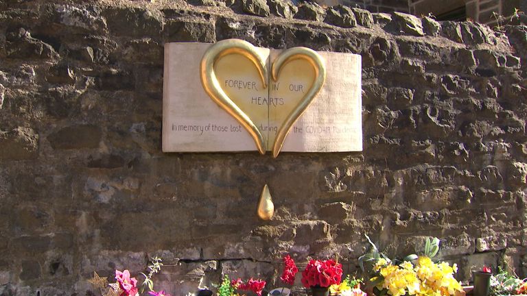 A memorial board lists the names of those who died from COVID-19