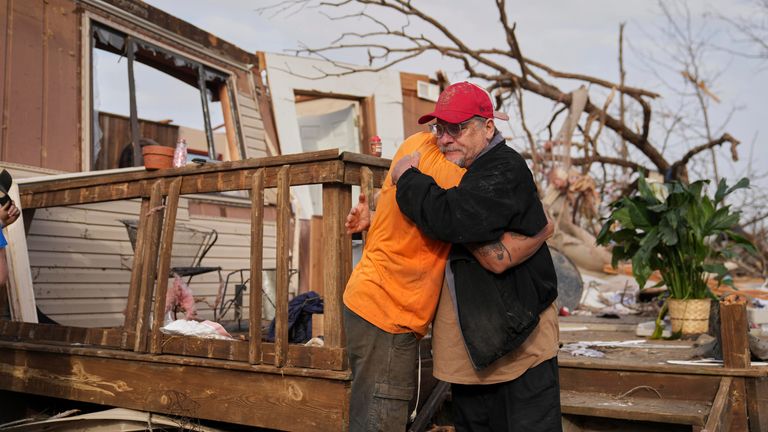 Tim Scott, right, gets a hug from friend Jorden Harris outside Scott's home he was inside when it was destroyed during a severe storm the evening before Saturday, March 15, 2025, in Wayne County, Mo. (AP Photo/Jeff Roberson)