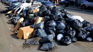 A man walks past a large pile of rubbish on the pavement of a street as strike action by Birmingham bin workers represented by the Unite union enters its third week in Birmingham, Britain, March 24, 2025. REUTERS/Phil Noble