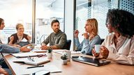 Business concept. Multinational professionals business people discussing daily topics by table in modern office. Business meeting.