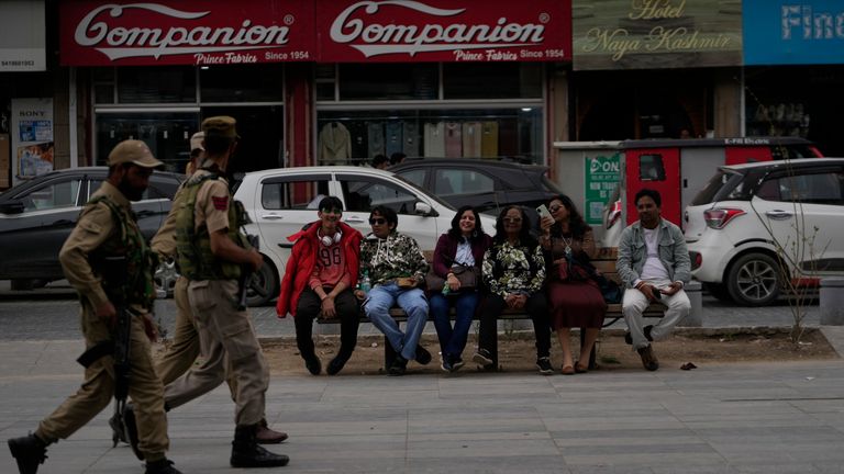 Indian tourists rests on a bench as policemen guard near a clock tower at city centre in Srinagar, Indian controlled Kashmir. Pic: AP