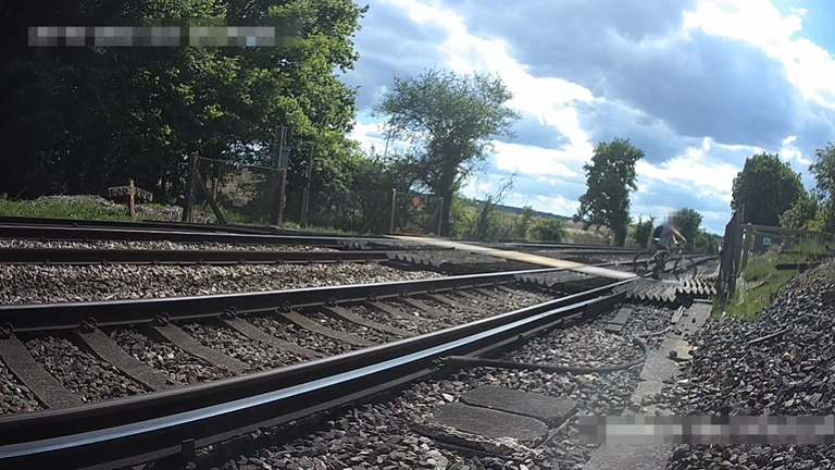 Rowerzysta patrzy na przychodzący pociąg, gdy przekracza kolej. PIC: Network Rail