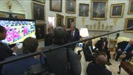 Ramaphosa, Trump and the gathered press watching the videos on a big screen in the Oval Office 