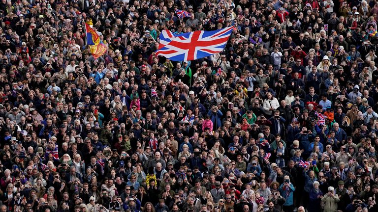 A person in the crowd waves a Union Jack flag, as members of the public walk up The Mall, near Buckingham Palace in central London, following a military procession marking the 80th anniversary of VE Day, and in honour of those who served during the Second World War, in central London, May 5, 2025. Andrew Matthews/Pool via REUTERS
