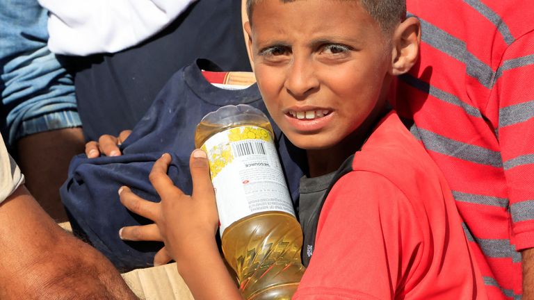 A youngster carries food aid as Palestinians seeking aid gather near an aid distribution site run by the U.S.-backed Gaza Humanitarian Foundation, in Rafah, in the southern Gaza Strip, May 27, 2025. REUTERS/Hatem Khaled