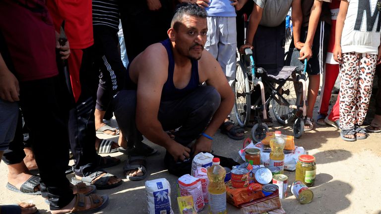 A person kneels next to food supplies as Palestinians seeking aid gather near an aid distribution site run by the U.S.-backed Gaza Humanitarian Foundation, in Rafah, in the southern Gaza Strip, May 27, 2025. REUTERS/Hatem Khaled