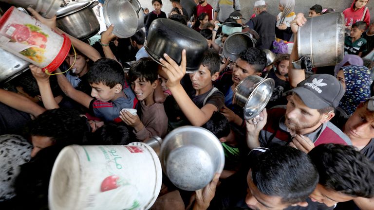 Palestinians wait to receive food cooked by a charity kitchen in Gaza.
Pic: Reuters