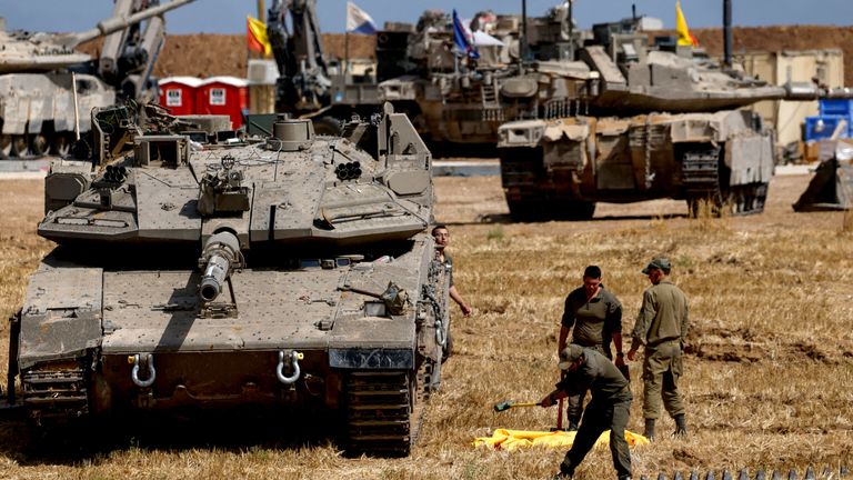Israeli soldiers work next to a tank near the Israel-Gaza border.
Pic: Reuters