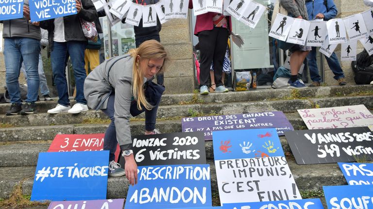 People place posters during a demonstration ahead of the verdict in the trial of Joel Le Scouarnec, a 74-year-old former surgeon, accused of raping and sexually assaulting 299 children, Wednesday, May 28, 2025 in Vannes, Brittany, western France. (AP Photo/Mathieu Pattier)