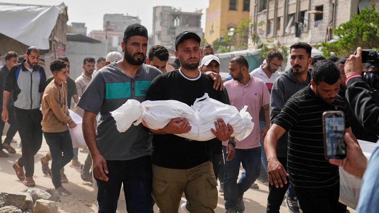Saleh Zenati, carries the body of his infant nephew Khalid Zenati killed in an Israeli army airstrike, during his funeral in Khan Younis, Gaza Strip, Sunday, May 18, 2025. (AP Photo/Abdel Kareem Hana)
