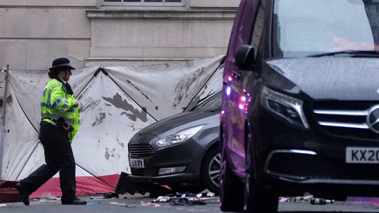 Un oficial de policía pasa junto a un transportista de personas grises después de que un automóvil se metió en una multitud en Liverpool.  Pic: AP