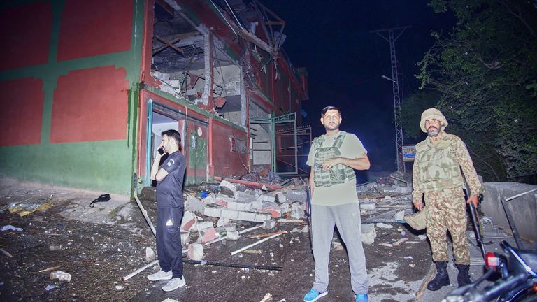 Security officials stand outside a damaged building at a site of a suspected Indian missile attack near Muzaffarabad, Kashmir
