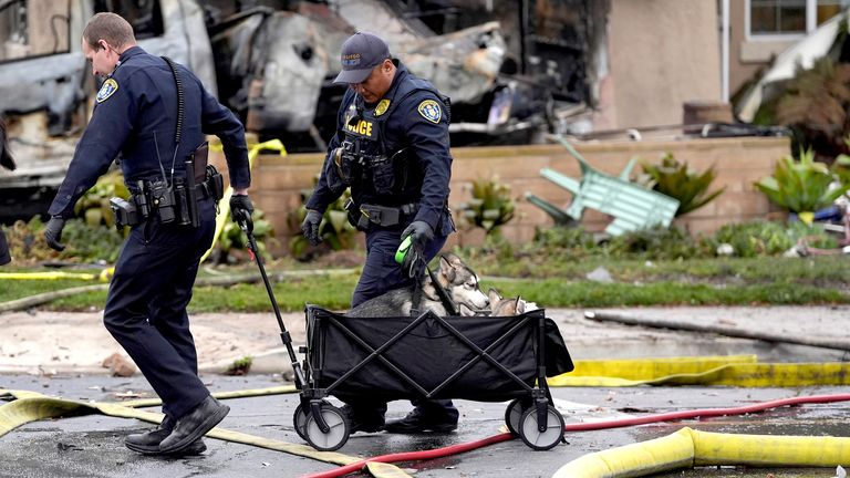 Police help rescue dogs from a home after a small plane crashed into a San Diego neighborhood earlier, setting several homes on fire and forcing evacuations along several blocks, Thursday, May 22, 2025. (AP Photo/Gregory Bull)