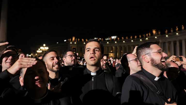 Faithful react to black smoke rising from the chimney on the Sistine Chapel indicating no decision has been made to elect a new pope, at the Vatican, May 7, 2025. REUTERS/Claudia Greco
