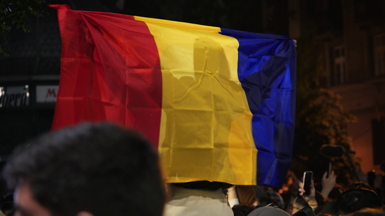 A man holds a Romanian flag in Bucharest