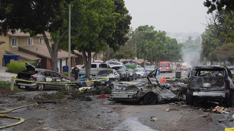 Authorities work the scene where a small plane crashed into a San Diego neighborhood, setting several homes on fire and forcing evacuations along several blocks early Thursday, May 22, 2025. (AP Photo/Gregory Bull)