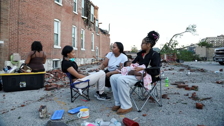 People sit outside their destroyed homes in St Louis, Missouri late on Friday. Pic: Reuters