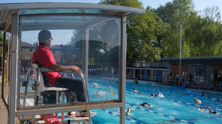 A life guard sits in a booth as people swim in the outdoor pool, as temperatures are expected to reach 27 degrees Celsius, at London Fields Lido in east London, Britain May 1, 2025. REUTERS/Vitalii Yalahuzian