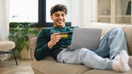 Man with credit card and laptop on sofa looking happy. Pic: iStock