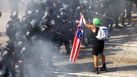 A demonstrator holds a U.S. flag opposite California Highway Patrol (CHP) officers, during a protest against federal immigration sweeps, in 