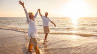 Happy senior man and woman old retired couple walking and holding hands on a beach at sunset. Pic: iStock