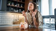 Hopeful young woman puts coin into her piggy bank. Pic: iStock