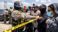 A Los Angeles County Sheriff's deputy holds back protesters in Paramount, Los Angeles on Saturday. Pic: Reuters
