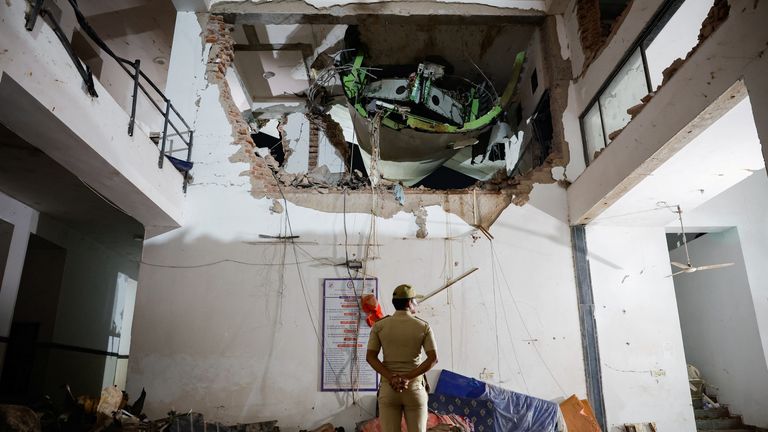 Police officer standing in front of Air India aircraft wreckage after crash near Ahmedabad airport. Pic: Reuters