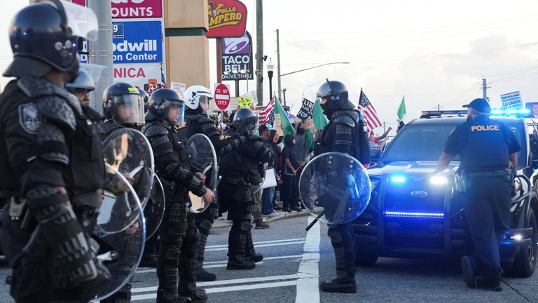 Kolluk personeli, Atlanta'daki federal göç taramalarına karşı bir protesto sırasında göstericiler toplandıkça nöbet tutuyor.  Pic: Reuters