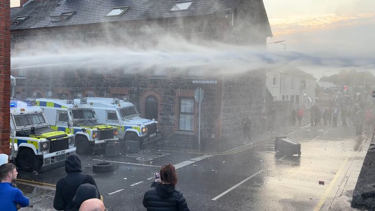 Police officers are using a water cannon to disperse protesters engaged in serious disorder. Pic: PA