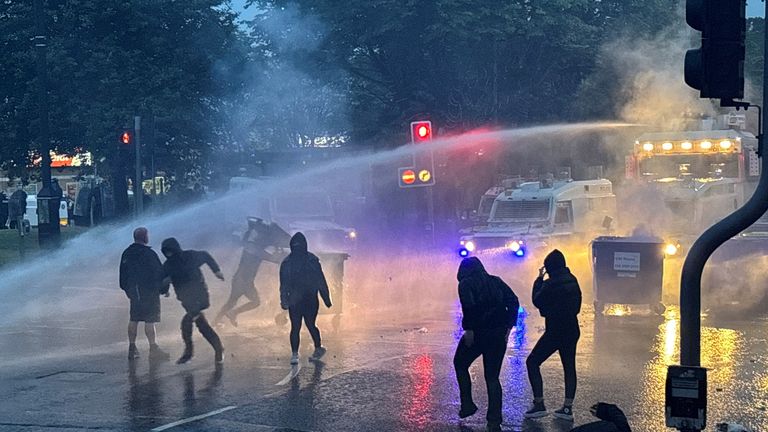 Police officers use a water cannon as the protest enters a second night. Pic: PA