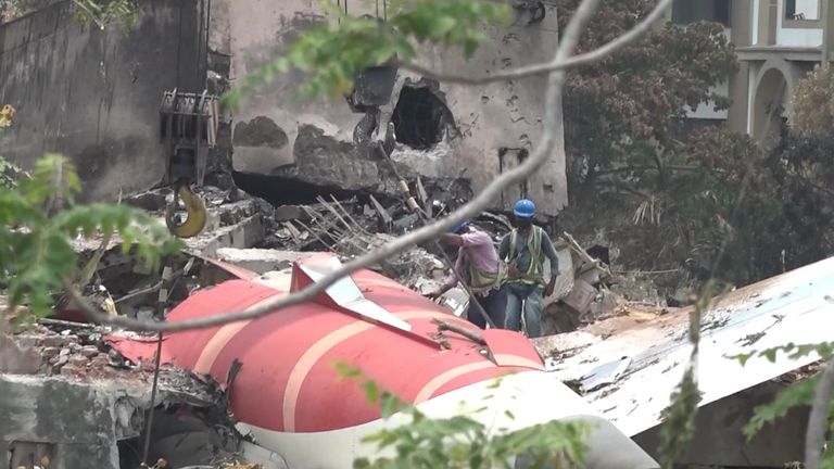 Men work to clear the ruins of Air India Boeing 787 Dreamliner after it crashed