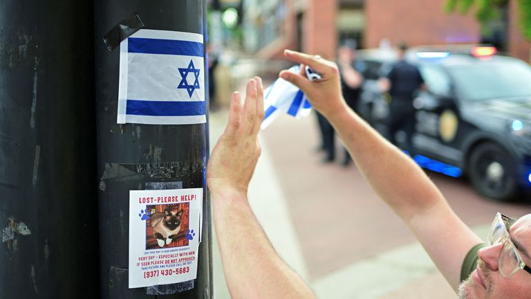 A man pins a stick of an Israeli flag to a post near the attack scene. Pic: Reuters