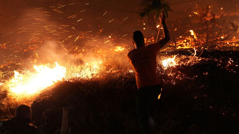 A man uses a branch to battle against a large wildfire burning in Kofinas, on the island of Chios, Greece.
Pic: Politischios/AP