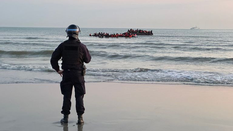 French police officer looks on as migrants in Dunkirk, France, prepare to cross the English Channel